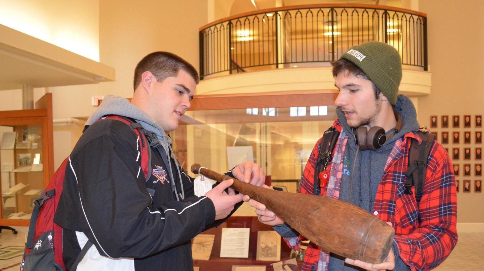 Two students examine a historic piece of pottery in the Springfield College experience.