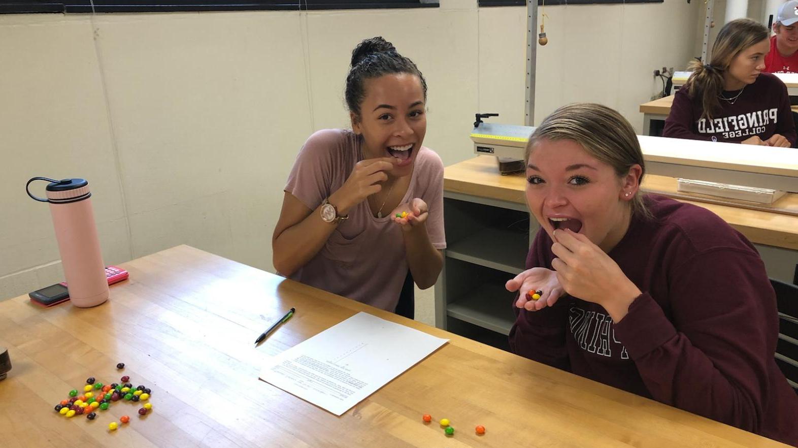 Two female students pretend to eat skittles during a math assignment