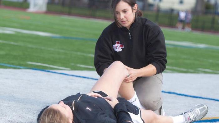 一个运动训练的学生在操场上伸展运动员的腿.